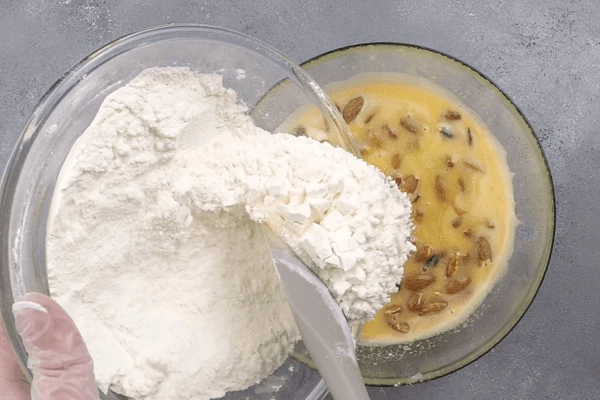 В яичную смесь добавить клюкву и орехи, затем всыпать муку и замесить пластичное тесто.