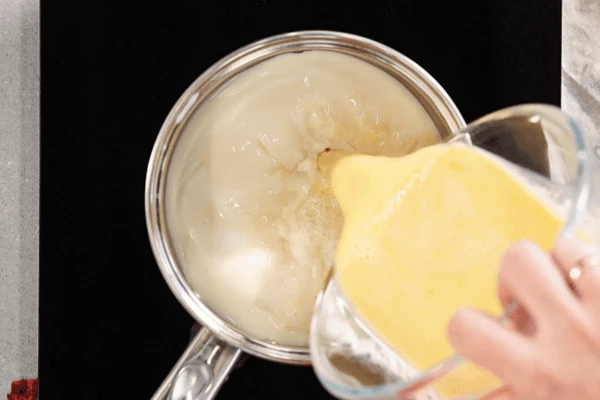 Вернуть в сотейник с оставшимся молоком на плиту, влить в него смесь яиц и молока, выставить минимальный нагрев. 