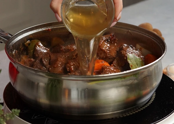 Влить часть бульона и тушить под крышкой на медленном огне в течение 3-4 часов, периодически подливая бульон. 
