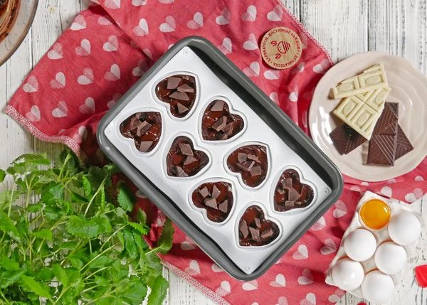 Разложить по формочкам. В каждую форморчу добавить кусочки темного шоколада. Выпекать в разогретой до 180 градусов духовке в течение 20 минут. Остудить. 

