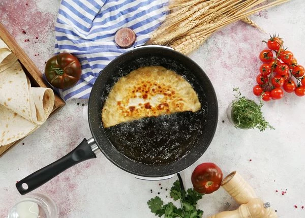 Тем временем нагреть в глубокой сковороде масло. Обжаривать чебуреки на среднем огне по 1,5-2 минуты с каждой стороны. Выложить на бумажные салфетки, чтобы убрать излишки масла. 
