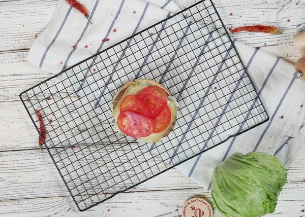 Затем выложить котлету с сыром и нарезанные томаты.