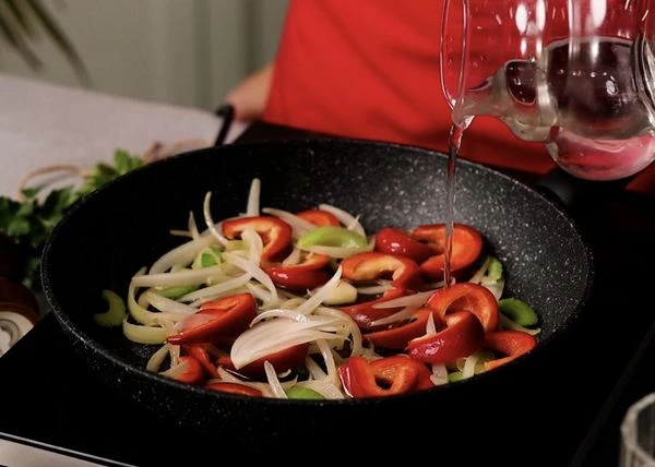 На сковороде разогреть оливковое масло и обжарить лук и сельдерей минут 5, пока они не станут немного мягкими.
Добавить перец к овощам, жарить еще пару минут, затем добавить раздавленный чеснок, влить воду и выпарить ее. 
