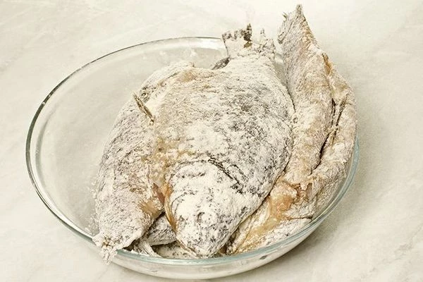Посолить, поперчить муку по вкусу, затем обвалять рыбу в получившейся смеси.