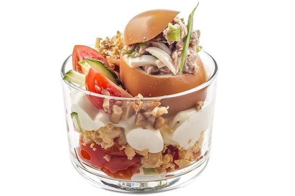 Яйцо наполнить начинкой и установить на горку с овощным салатом. Украсить зеленым луком, дольками помидора черри и рубленым грецким орехом.