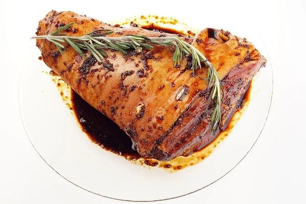 Сделайте в коже по всему периметру небольшие проколы ножом, нашпигуйте дольками чеснока. Затем обмажьте рульку маринадом. Положите в пакет для запекания с веточкой розмарина, дайте полежать минут 30 в маринаде при комнатной температуре.