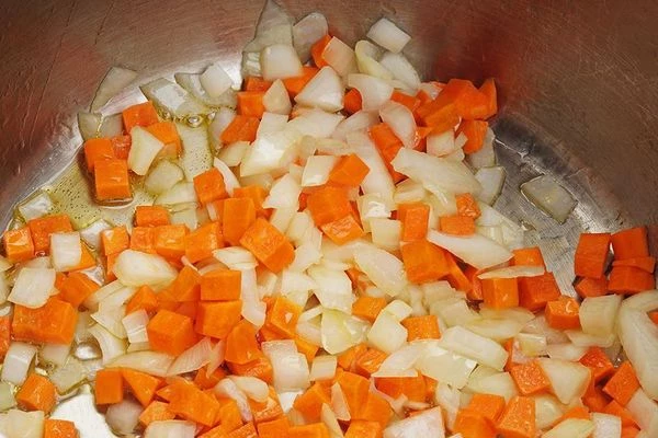 В глубокой кастрюле разогреть растительное масло, обжарить лук и морковь до золотистого цвета.