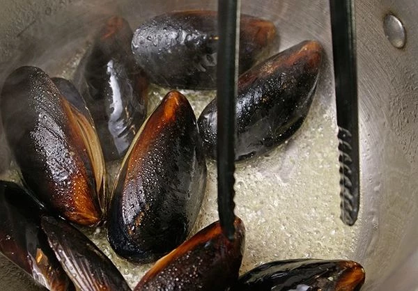 В кастрюле разогреть оливковое масло, обжарить мидии 1-2 минуты.