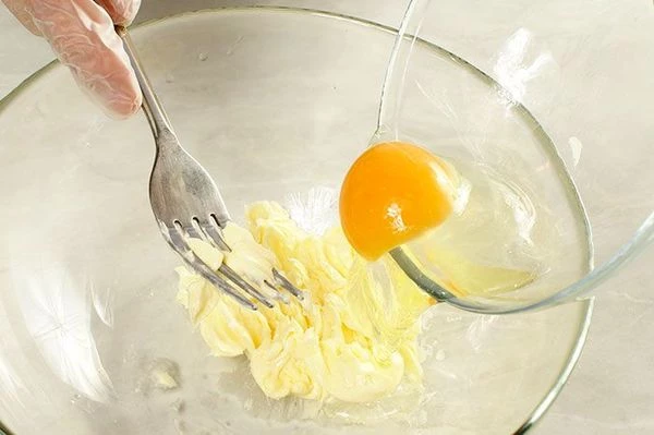 В чашке взбить размягченное сливочное масло с солью, затем вмешать туда 2 яйца.