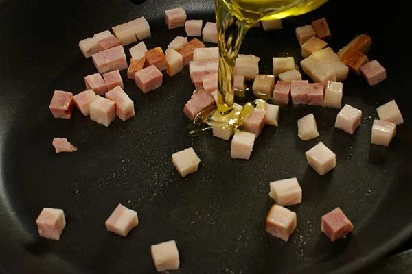 Бекон обжарить на разогретой сковороде, чтобы слегка вытопился жир, затем добавить оливковое масло.