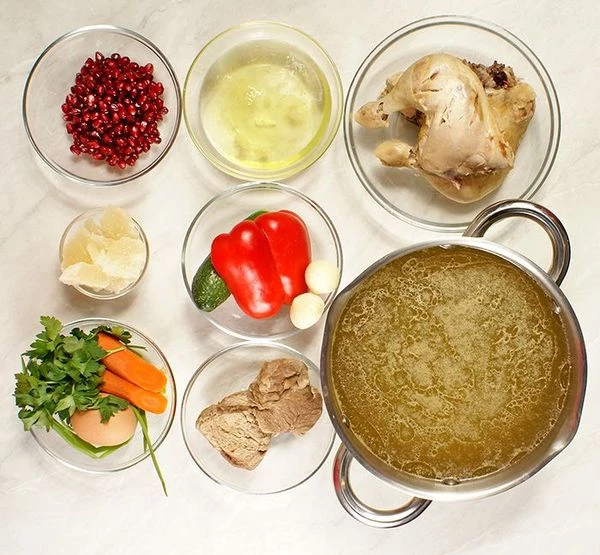 Приготовить мясной бульон: в кастрюлю с холодной водой положить курицу, свинину, нарезанные и подпеченные лук и морковь, хвостики от петрушки и укропа, перец горошком. Варить до готовности мяса. В конце добавить порубленный мелко чеснок. Снять с огня.
Желатин замочить в небольшом количестве остывшего бульона. Приготовить овощи для оформления.