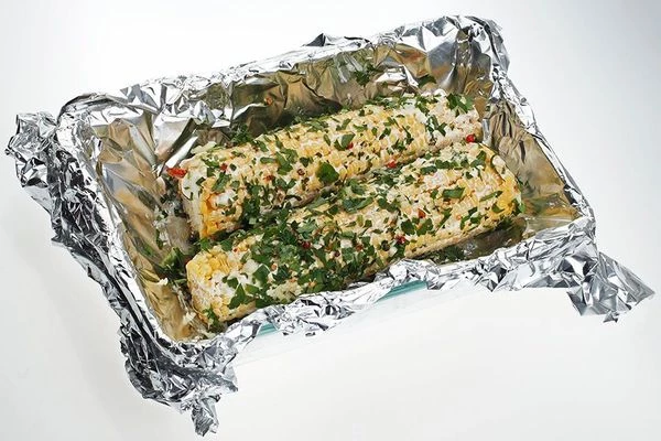 Обмазать кукурузу со всех сторон смесью масла и специй. Завернуть в фольгу.