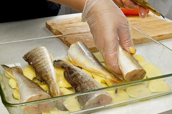 На смазанный растительным маслом  противень для запекания выложить картофель, сверху уложить размороженную и промытую навагу. Посолить, поперчить по вкусу.