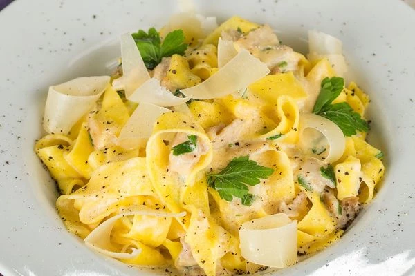 Готовую пасту выложить в тарелку, украсить слайсами сыра и черным свежемолотым перцем.