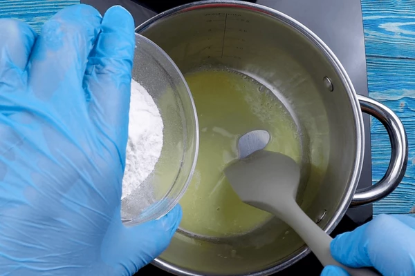  Приготовить соус бешамель: в глубокой кастрюльке разогреть сливочное масло, постепенно всыпать, помешивая, муку.