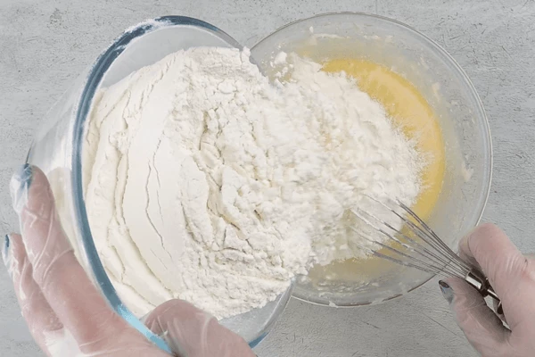 К масляной основе добавить просеянную муку с разрыхлителем и быстро замесить тесто.