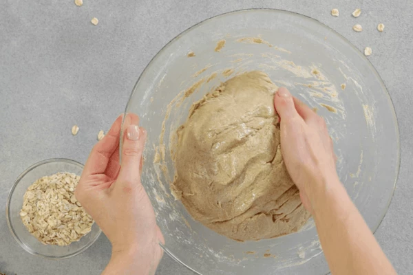 Вымесить тесто. Скатать его в шар, поместить в емкость, смазанную маслом, накрыть пленкой. 