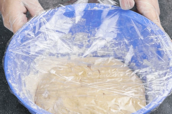 Скатать тесто в шар, накрыть пищевой пленкой и поставить в теплое место для подъема на час.