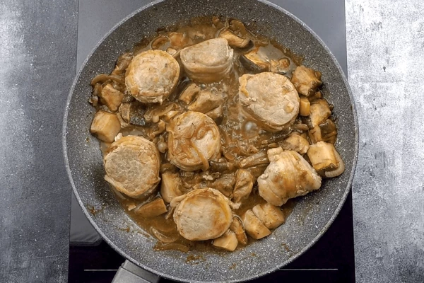 Добавить к грибам соус, выложить сверху медальоны без шпажек и довести мясо до готовности.