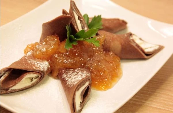 Получившиеся блинчики охладить, выложить начинку из сливочного сыра, завернуть в трубочки. Разрезать по диагонали, выложить на тарелку. Украсить джемом , мятой и сахарной пудрой.