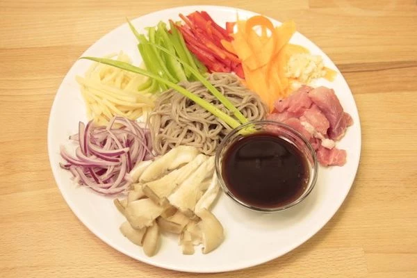 Свинину размораживаем, обмываем, просушиваем и нарезаем тонкой соломкой. Грибы разбираем на тонкие волокна. Чеснок мелко рубим. Перец и лук режем тонкой соломкой. Морковь нарезаем тонкими пластинками с помощью обычной овощерезки.