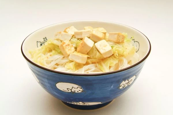 Добавить к рисовой лапше отваренную пекинскую капусту вместе с овощным бульоном, а сверху выложить обжаренный тофу.

