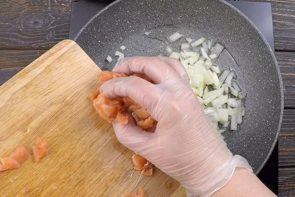 На хорошо разогретой с растительным маслом сковороде обжарить лук, затем добавить чеснок и рыбу, обжарить 2-3 минуты. Посолить, поперчить по вкусу. Снять с огня, охладить до комнатной температуры. 