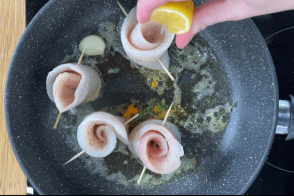 В масло выложить рулеты из хека, сбрызнуть соком лимона. 
