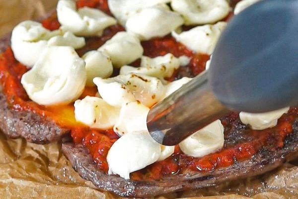 Сверху выложить кусочки моцареллы и опалить горелкой. 