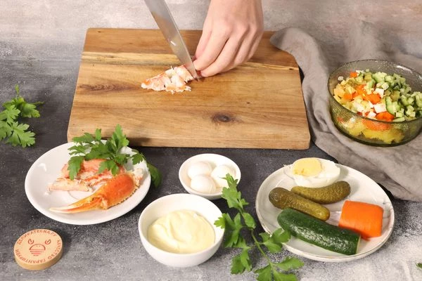 Конечности краба и рыбу разморозьте на нижней полке холодильника. Из конечностей краба достаньте мясо и порежьте его кубиками — 0,5х0,5 см. Переложите к овощам.