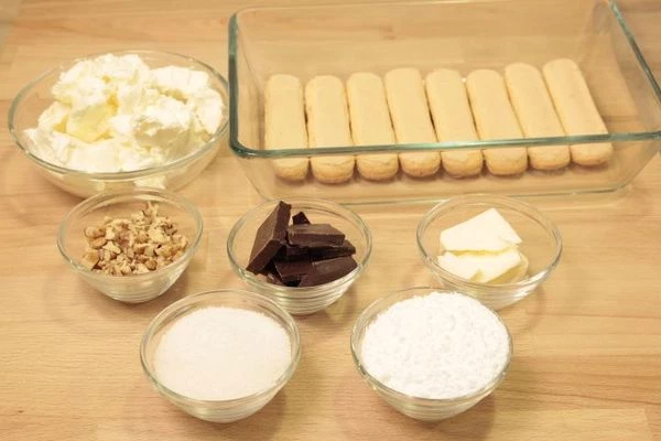 Желатин замочить в холодной воде на 10 минут. Шоколад поломать на кусочки, смешать с сливочным маслом. Сыр смешать с сахарной пудрой. 2/3 орехов  мелко порубить ножом.