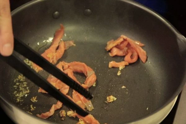 На раскаленную сковороду влить оливковое масло с тертым чесноком, добавить помидоры черри и слабосоленую рыбу. Слегка обжарить и влить рыбный бульон. Затем добавить пасту, выпарить 2-3 минуты.