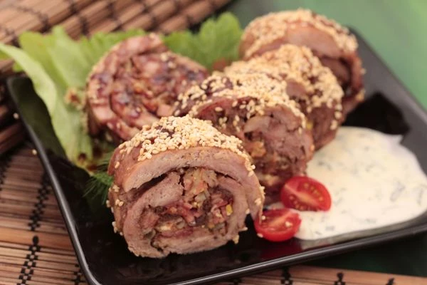 Готовый рулет освободить от фольги, обсыпать по всей поверхности кунжутом. Нарезать на порционные кусочки.