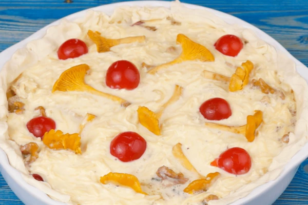 Сформировать края теста, украсить несколькими половинками помидор и отложенных грибов.  Поставить в разогретую до 190-200С духовку, запекать до готовности (примерно 20-25 минут).