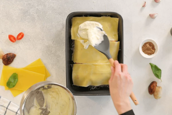 Затем листы лазаньи, белый соус, посыпать мускатным орехом и тертым пармезаном.