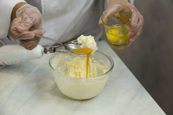 Не переставая взбивать, добавьте к маслу по 1 яйцу.