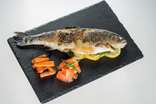 Готовую рыбу выложить на тарелку, украсить брусочками моркови, свежими овощами и зеленью.