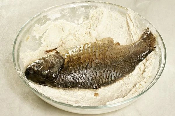 Карасей разморозить естественным способом на нижней полке холодильника, почистить от чешуи, разрезать вдоль брюшка, удалить внутренности. Промыть рыбу под холодной водой, обсушить бумажным полотенцем.