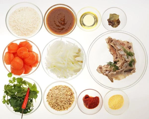 Бараньи ребра промыть, залить холодной водой, варить до готовности (50-60 минут). Помидоры обдать кипятком и снять кожицу, лук почистить и нарезать мелко. Грецкие орехи порубить.