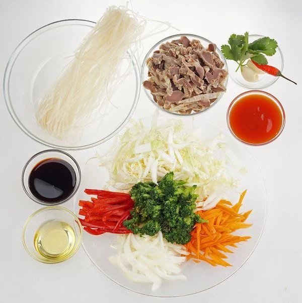 Куриные желудки промыть, залить холодной водой и варить 1-2 часа до готовности. Овощи нарезать тонкой соломкой. Рисовую лапшу отварить в кипящей подсоленной воде 3 минуты, затем залить холодной водой и слить через дуршлаг.