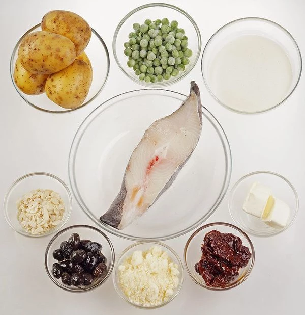 Стейк палтуса разморозить естественным способом на нижней полке холодильника, промыть, обсушить бумажным полотенцем. Картофель почистить, вяленые помидоры и оливки нарезать тонкой соломкой.