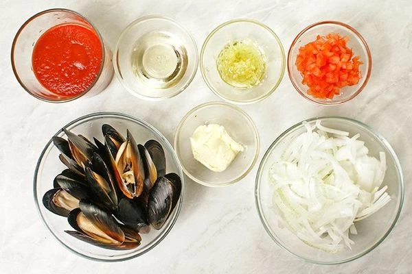 Репчатый лук нарезать тонкой соломкой, помидоры разрезать пополам и удалить семена, нарезать мелким кубиком. Чеснок натереть и смешать с оливковым маслом.