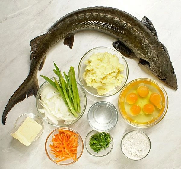 Картофель отварить в подсоленной воде, приготовить густое пюре, добавить яйцо, остудить. Осетра промыть от слизи, вырезать жабры. Натереть солью, дать полежать 5-10 минут. Лук репчатый и морковь нарезать тонкой соломкой.