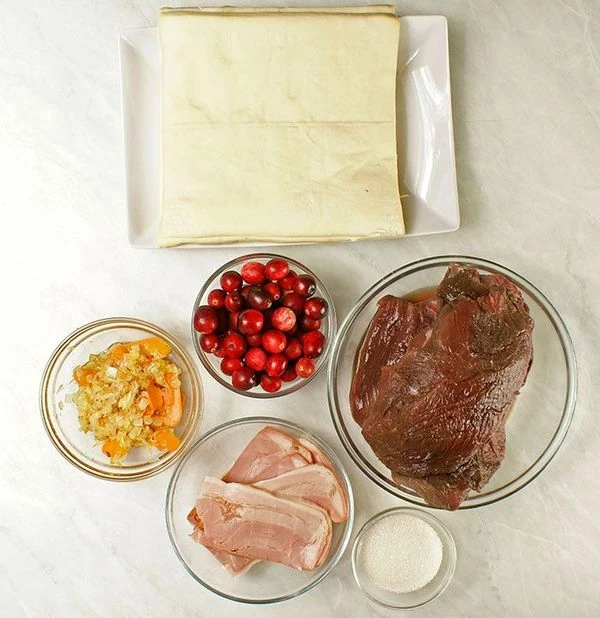 Мясо оленя разморозить естественным способом на нижней полке холодильника. Зачистить от пленок и сухожилий. Выбрать крупные кусочки, убрать в холодильник на сутки, замариновав в смеси уксуса и воды. Лук и морковь нарезать крупно, обжарить на разогретой с оливковым маслом сковороде.