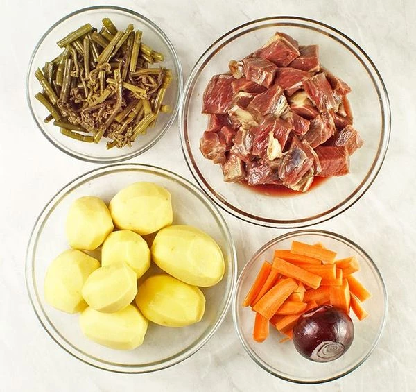 Мясо жеребенка разморозить естественным способом на нижней полке холодильника. Нарезать крупными кубиками, замариновать в смеси специй и оливковом масле на 30-40 минут. Папоротник вымочить в горячей воде в течение 12 часов, периодически меняя воду. Овощи (картофель, лук, морковь) почистить.