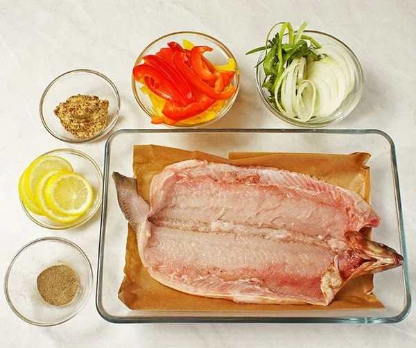 Рыбу разморозить естественным способом на нижней полке холодильника. Разрезать по брюшку, удалить внутренности, жабры, промыть. Аккуратно ножницами подрезать хребет около хвостового плавника и около головы, удалить вместе с костями. 