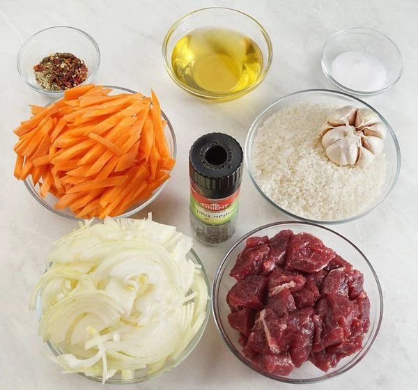 Морковь нарезать толстой, длинной соломкой толщиной 0,5х0,5 см, лук нарезать полукольцами. Говядину нарезать крупным кубиком. Чеснок промойте, не очищайте.