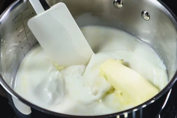 В кастрюле смешать воду, молоко, сливочное масло, довести до кипения на слабом огне. 