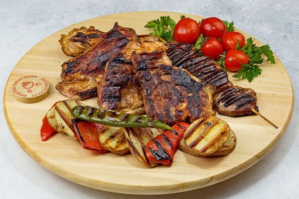 Овощи гриль выложить к мясу, украсить по желанию зеленью и помидорками.