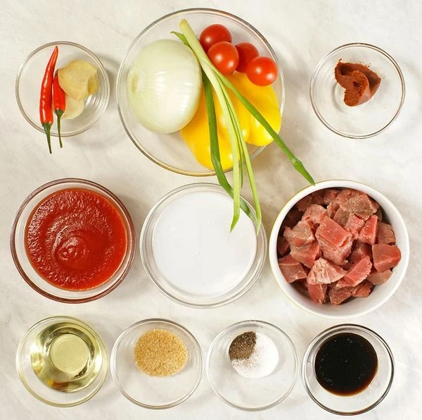 Мясо разморозить естественным способом на нижней полке холодильника, нарезать небольшими кубиками, лук и чеснок почистить. У перца чили и желтого перца удалить семена.